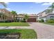 Beautiful single Gathering home featuring a well-manicured lawn, brick driveway, and attached two-car garage at 10880 Cory Lake Dr, Tampa, FL 33647