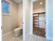Half bath with a toilet and a view into a closet with wooden shelving at 1204 Derby Ln, Sarasota, FL 34242