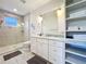 Bright bathroom featuring a walk-in shower, double sink vanity, and built-in storage shelves at 1204 Derby Ln, Sarasota, FL 34242