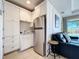 Compact kitchenette area with white cabinetry, stainless steel refrigerator, and adjacent seating at 1204 Derby Ln, Sarasota, FL 34242