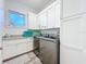 Bright laundry room with ample white cabinetry, granite countertops, and stainless steel washer and dryer at 1204 Derby Ln, Sarasota, FL 34242