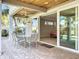 A covered patio features a ceiling fan and a dining table with chairs next to sliding glass doors to the main bedroom at 1204 Derby Ln, Sarasota, FL 34242