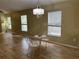 Open dining area with wood-look floors and windows, complemented by a charming chandelier at 15421 Shoal Haven Pl, Ruskin, FL 33573