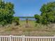 Scenic backyard view with a white fence overlooking a serene lake, framed by lush greenery for privacy at 1701 Bonita Bluff Ct, Ruskin, FL 33570