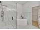 Modern bathroom featuring a glass enclosed shower and a freestanding tub, complemented by marble accents and a spacious walk-in closet at 1729 Arabian Ln, Palm Harbor, FL 34685