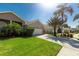 Charming home featuring a well-manicured lawn, lush tropical plants, and a spacious driveway to the two-car garage at 1729 Arabian Ln, Palm Harbor, FL 34685
