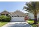 Attractive house featuring a manicured yard, swaying palm tree, and a wide driveway to the two-car garage at 1729 Arabian Ln, Palm Harbor, FL 34685