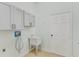 Functional laundry room with upper cabinets, a utility sink, and a white door, offering practicality and storage at 1729 Arabian Ln, Palm Harbor, FL 34685
