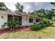 Charming single-story home with manicured lawn, vibrant landscaping, and a welcoming screened-in porch entrance at 17631 Grove View Dr, Lutz, FL 33549