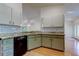 Well-lit kitchen featuring wood floors, vintage green cabinets, granite counters, and a sleek black dishwasher at 17631 Grove View Dr, Lutz, FL 33549