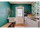 Stylish laundry room with emerald walls, a utility sink, and a modern washer and dryer at 17631 Grove View Dr, Lutz, FL 33549