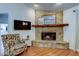 Cozy living room with stone fireplace, wooden mantel, flat screen TV, and decorative chair at 17631 Grove View Dr, Lutz, FL 33549