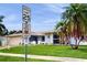 Street view of a light blue single-story home showing the front lawn, palm trees, and an attached garage at 206 Hillcrest Dr, Safety Harbor, FL 34695