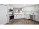 Well-lit kitchen with stainless appliances, white cabinetry and wood-look laminate flooring at 2108 Delightful Dr, Ruskin, FL 33570