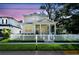 Inviting two-story home with a charming front porch, white picket fence, and picturesque curb appeal at dusk at 238 7Th S Ave, Safety Harbor, FL 34695