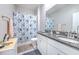 Bathroom featuring double sinks with granite countertops, white cabinets, and a shower-tub with a blue shower curtain at 25200 Lambrusco Loop, Lutz, FL 33559