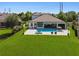 Aerial view of the pool with in-water seating, the patio, and the home's backyard at 2648 Lake Manor Dr, Land O Lakes, FL 34639