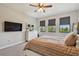 Bright bedroom features a ceiling fan, a TV, and three windows with wooded views at 2648 Lake Manor Dr, Land O Lakes, FL 34639