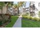 Exterior view of a multi-story building with lush tropical landscaping and a sidewalk at 2650 Countryside Blvd # C204, Clearwater, FL 33761