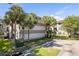 View of condominium exterior with mature palm trees, a parking area, and green space at 2650 Countryside Blvd # C204, Clearwater, FL 33761