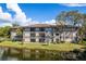 Exterior view of a condo building with a lake and landscaping in a waterfront setting at 2650 Countryside Blvd # C204, Clearwater, FL 33761