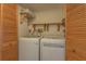 Bright laundry room featuring a side-by-side washer and dryer, wooden louvered closet doors, and wooden shelving at 2650 Countryside Blvd # C204, Clearwater, FL 33761