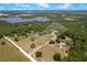 An aerial view reveals the home surrounded by lush trees, open fields, and a serene lake nearby at 31949 Amberlea Rd, Dade City, FL 33523