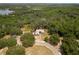Aerial view of the home nestled within a lush, green landscape featuring mature trees and a serene pond at 31949 Amberlea Rd, Dade City, FL 33523