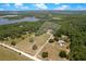 An aerial view shows the lake community with open fields, green trees, and roads in the distance at 31949 Amberlea Rd, Dade City, FL 33523