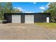 Metal building with two large roll-up doors, ideal for storage or workshop purposes, set on a gravel lot at 31949 Amberlea Rd, Dade City, FL 33523