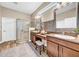 A stylish bathroom with a tiled shower, dual sinks, and wood-style flooring at 32624 Summerglade Dr, Wesley Chapel, FL 33545