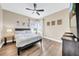 Bedroom with a bed, wood floors, a fan, two windows with white drapes, and decorative art at 32624 Summerglade Dr, Wesley Chapel, FL 33545