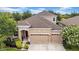 Two-story tan home with three car garage, red front door, and well maintained landscaping at 32624 Summerglade Dr, Wesley Chapel, FL 33545