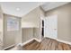 Hallway with light walls, wood floors, a window with blinds, and a partially opened door at 32624 Summerglade Dr, Wesley Chapel, FL 33545