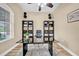 Well-lit home office with a black glass-top desk, ample storage shelves, and stylish decor at 32624 Summerglade Dr, Wesley Chapel, FL 33545