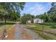 Quaint single-story home featuring a gravel driveway leading to a cozy residence, surrounded by lush greenery and trees at 3373 Olson Rd, Spring Hill, FL 34607