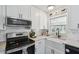 Well-lit kitchen featuring white cabinets and a farmhouse style sink with stainless steel appliances at 3628 Dellefield St, New Port Richey, FL 34655