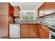 Kitchen featuring wooden cabinets, granite countertops, a stainless steel dishwasher, and a window at 3641 Coppertree Cir, Brandon, FL 33511