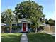 Charming single-story home with a vibrant red door, lush landscaping, and two palm trees accenting the front yard at 3980 55Th N Ave, St Petersburg, FL 33714