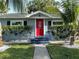 Cozy single-story home featuring a bright red front door, tidy landscaping, and tropical palm trees at 3980 55Th N Ave, St Petersburg, FL 33714