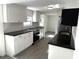 Stylish kitchen featuring black granite countertops, white cabinets, stainless steel appliances, and gray wood-look floors at 3980 55Th N Ave, St Petersburg, FL 33714
