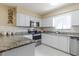A well-lit kitchen featuring white cabinets, stainless steel appliances, granite countertops, and white tiled backsplash at 4030 Cortez Dr # C, Tampa, FL 33614
