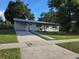 Single-story home featuring a well-manicured lawn, covered parking, and a paved walkway at 4104 W Wisconsin Ave, Tampa, FL 33616