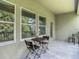 Tiled outdoor balcony featuring a table and chairs, and views through the windows to the lush trees and sky at 4567 Tuscan Loon Dr, Tampa, FL 33619