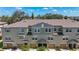 Image showcasing a row of tan and green townhomes, each equipped with individual garages and landscaping at 4567 Tuscan Loon Dr, Tampa, FL 33619