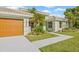 Beautiful one-story home with a large two car garage, a light green exterior, and tropical landscaping at 5002 E Longboat Blvd, Tampa, FL 33615