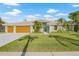Beautiful one-story home with a large two car garage, a light green exterior, and tropical landscaping at 5002 E Longboat Blvd, Tampa, FL 33615