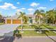 Beautiful one-story home with a large two car garage, a light green exterior, and tropical landscaping at 5002 E Longboat Blvd, Tampa, FL 33615
