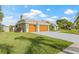 Beautiful single-story house with a gray driveway, brown garage doors, and a green lawn at 5002 E Longboat Blvd, Tampa, FL 33615