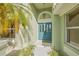 Close up of a turquoise front door with glass panels, tropical landscaping, and a bright interior at 5002 E Longboat Blvd, Tampa, FL 33615